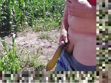 Making a piss balloon with black condom in corn field